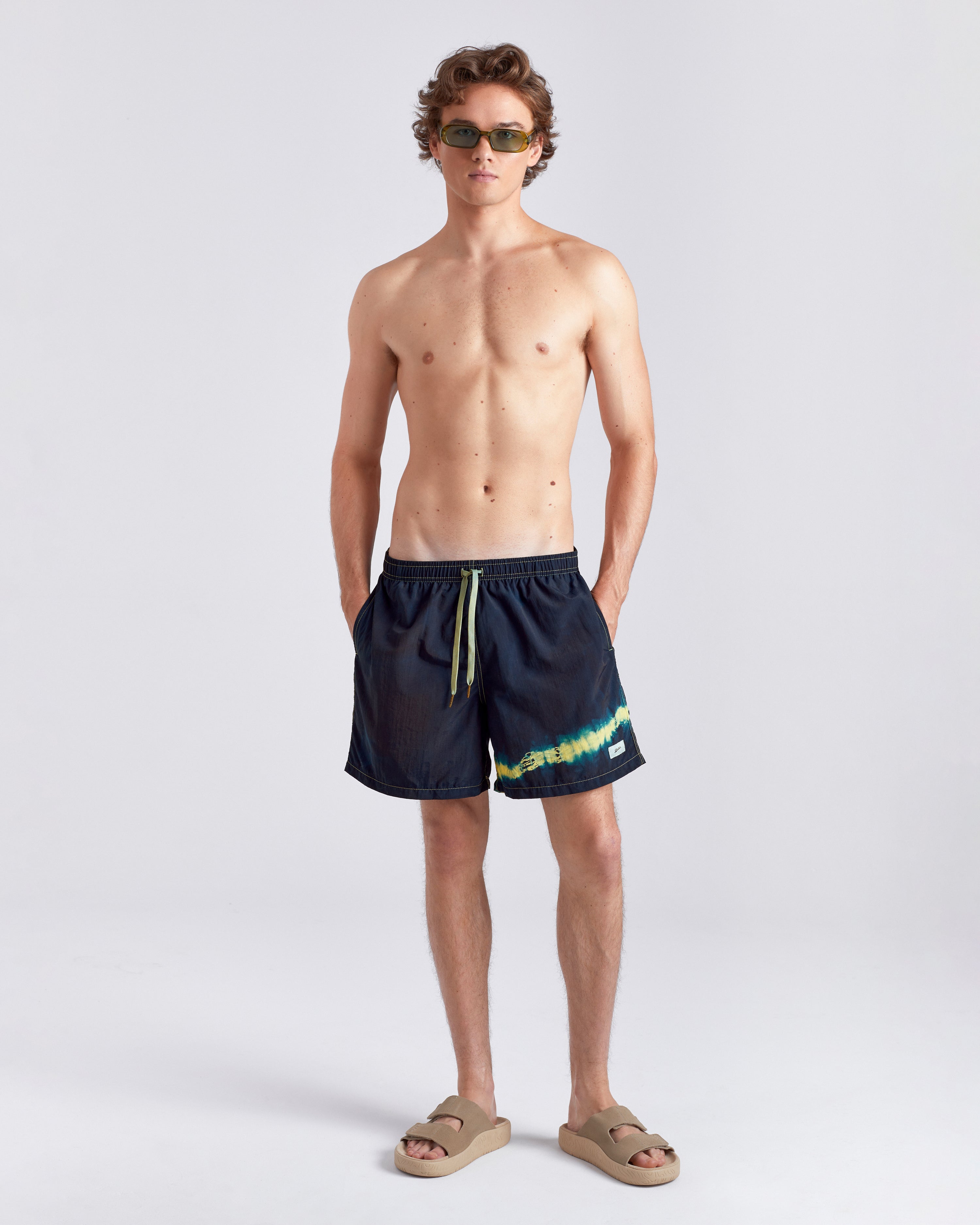 Man wearing navy swim shorts with a colorful stripe on a white background
