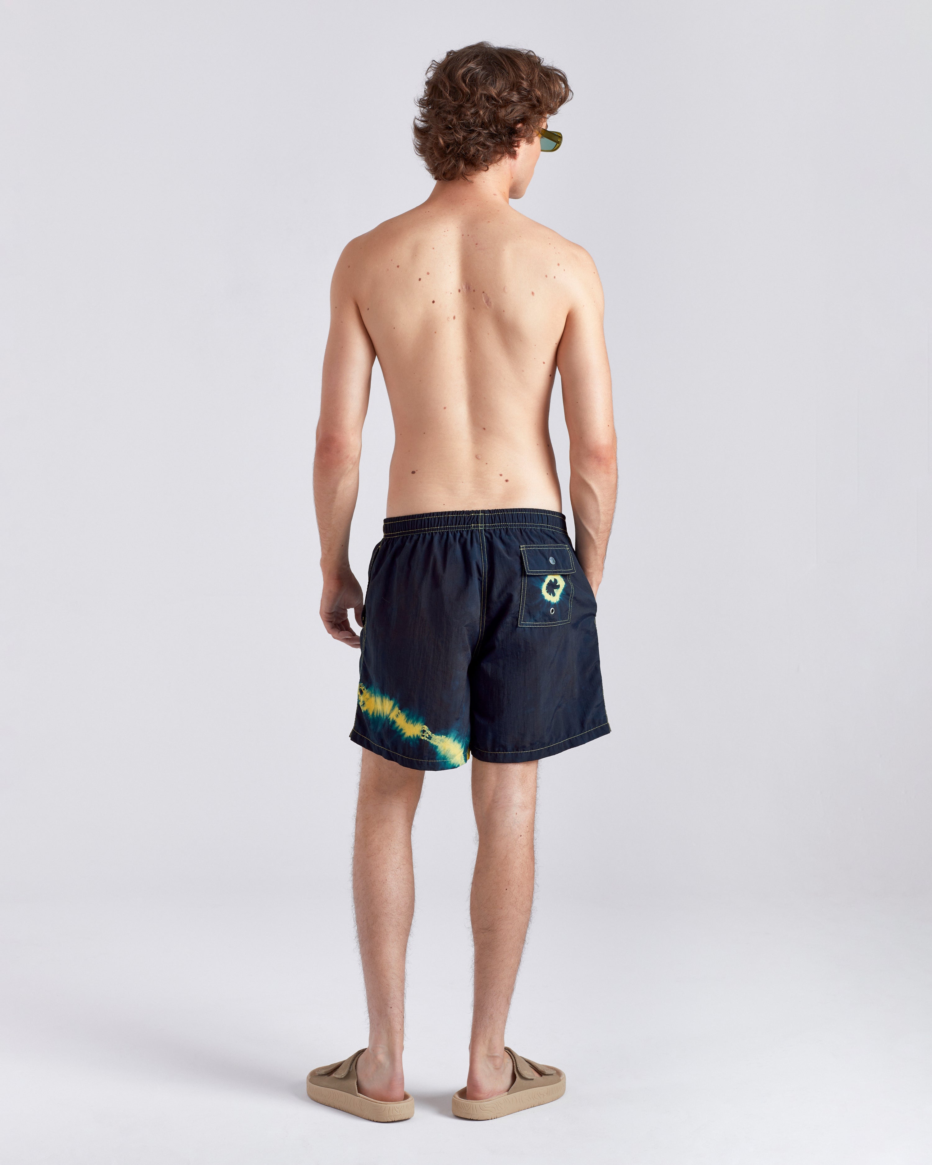 Man wearing indigo swim shorts with a colorful design on a white background