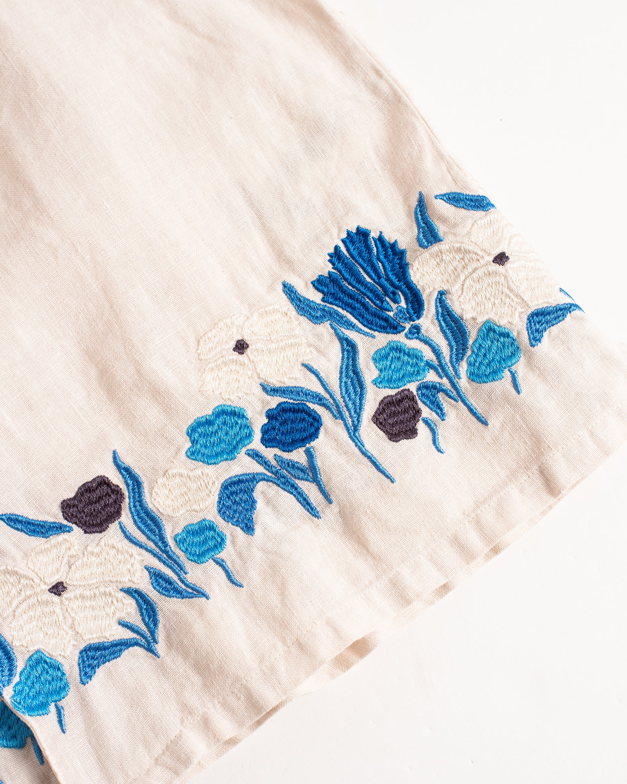 Close-up of a white fabric with blue floral embroidery on a white background
