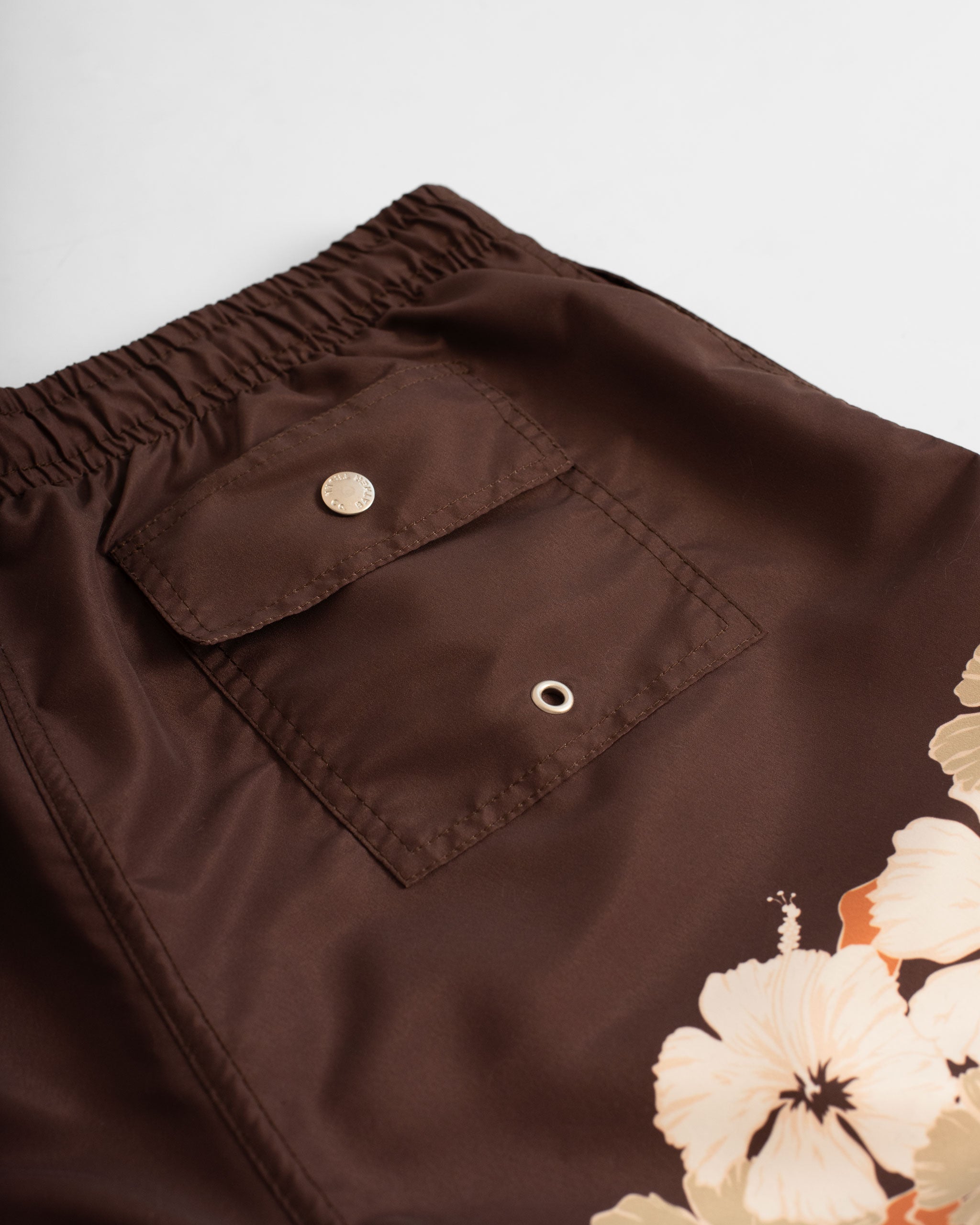 back pocket shot of Brown swim trunk with floral print on the bottom of the leg