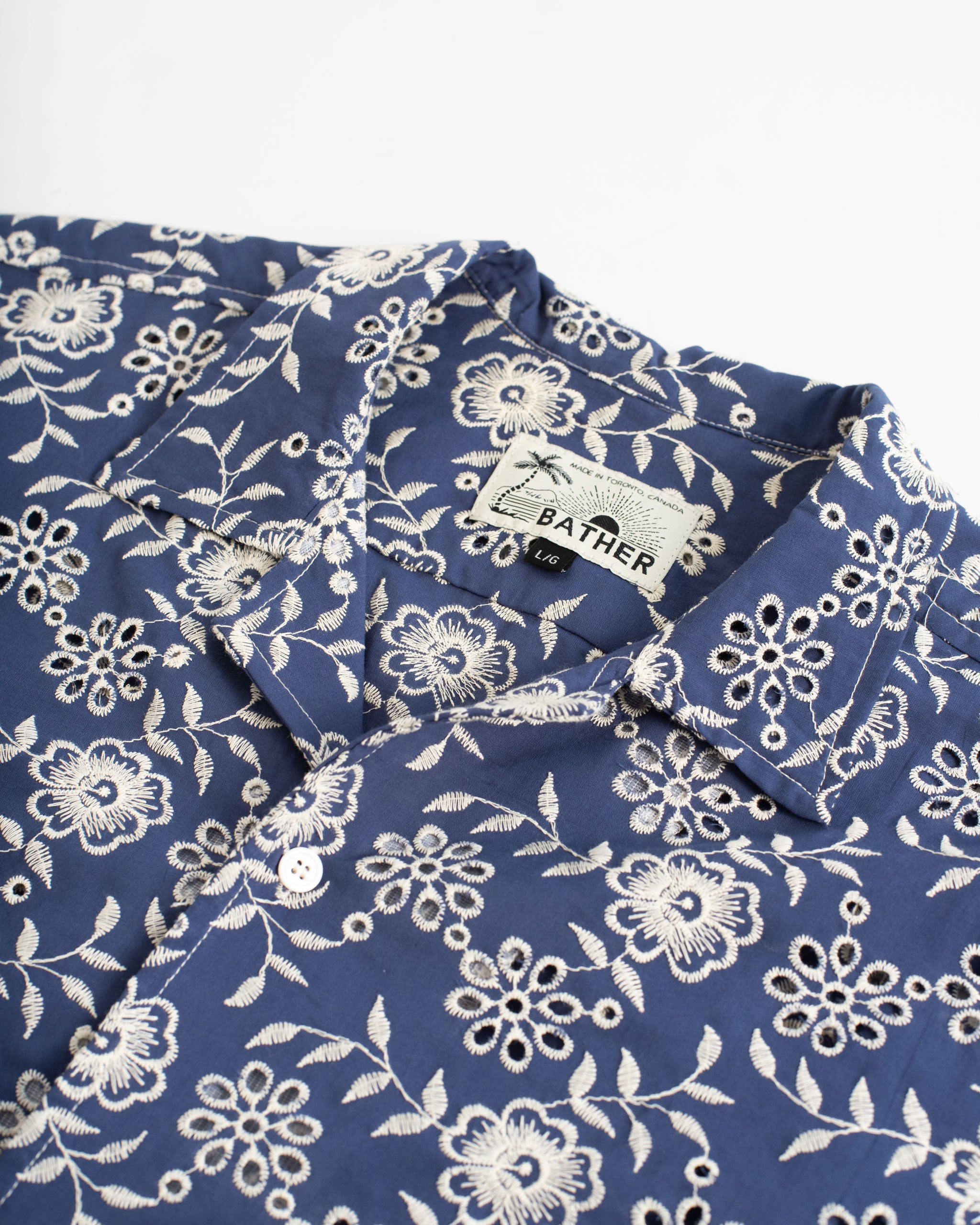 collar close up of Blue camp shirt with an embroidered floral pattern