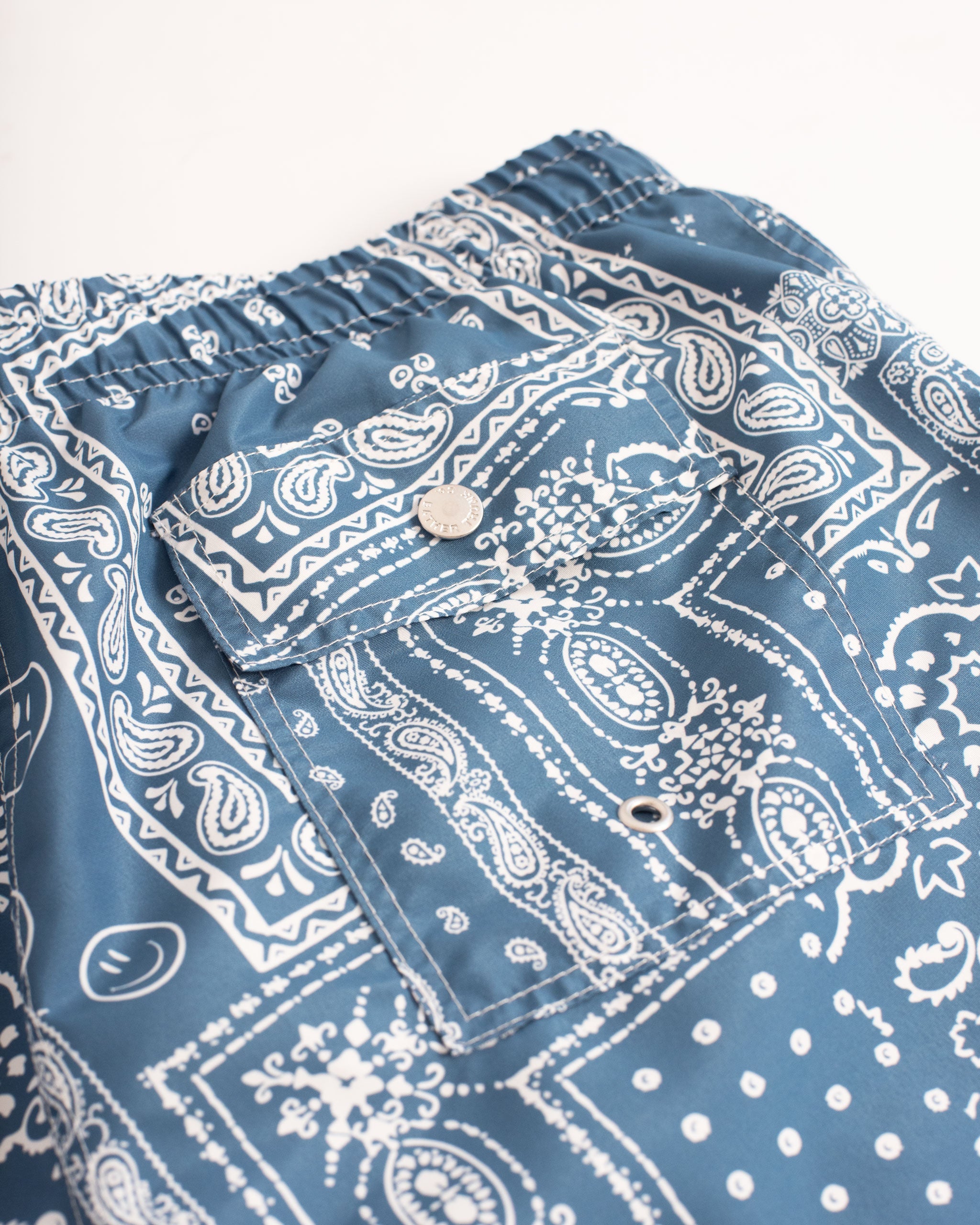 Back pocket close up of Blue swim trunk with all-over bandana print