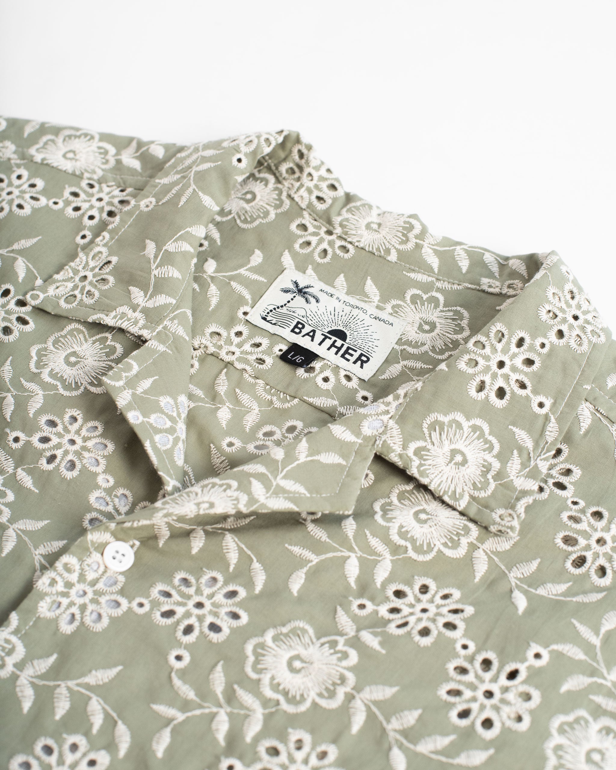 A sage green camp shirt with an all-over embroidered floral pattern collar close up